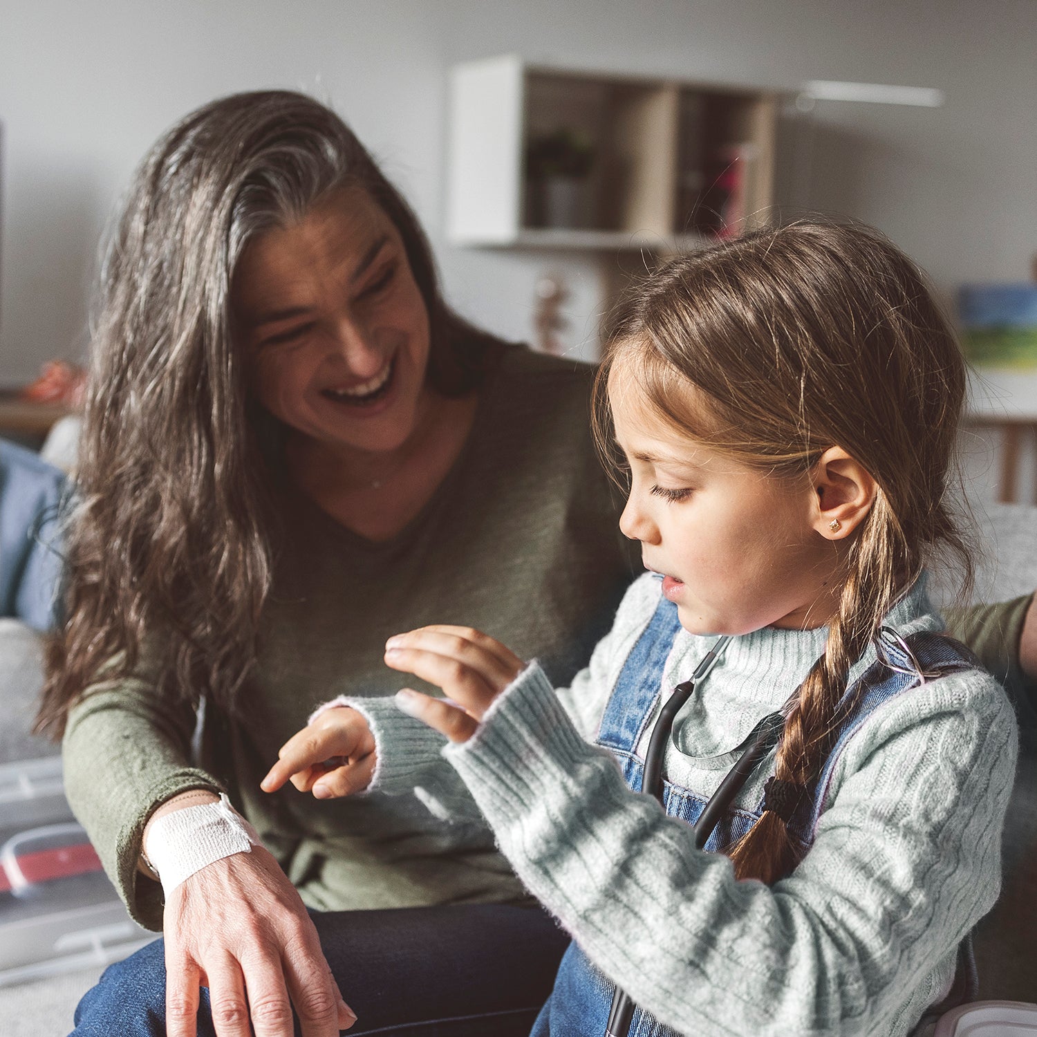 Woman and young girl sitting together, smiling and interacting in a home setting. while treating a wound with rapid seal wound gel