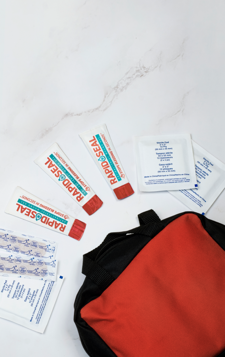 picture of a first aid kit with rapid seal pakcets and bandages coming out of it as well as gauze pads